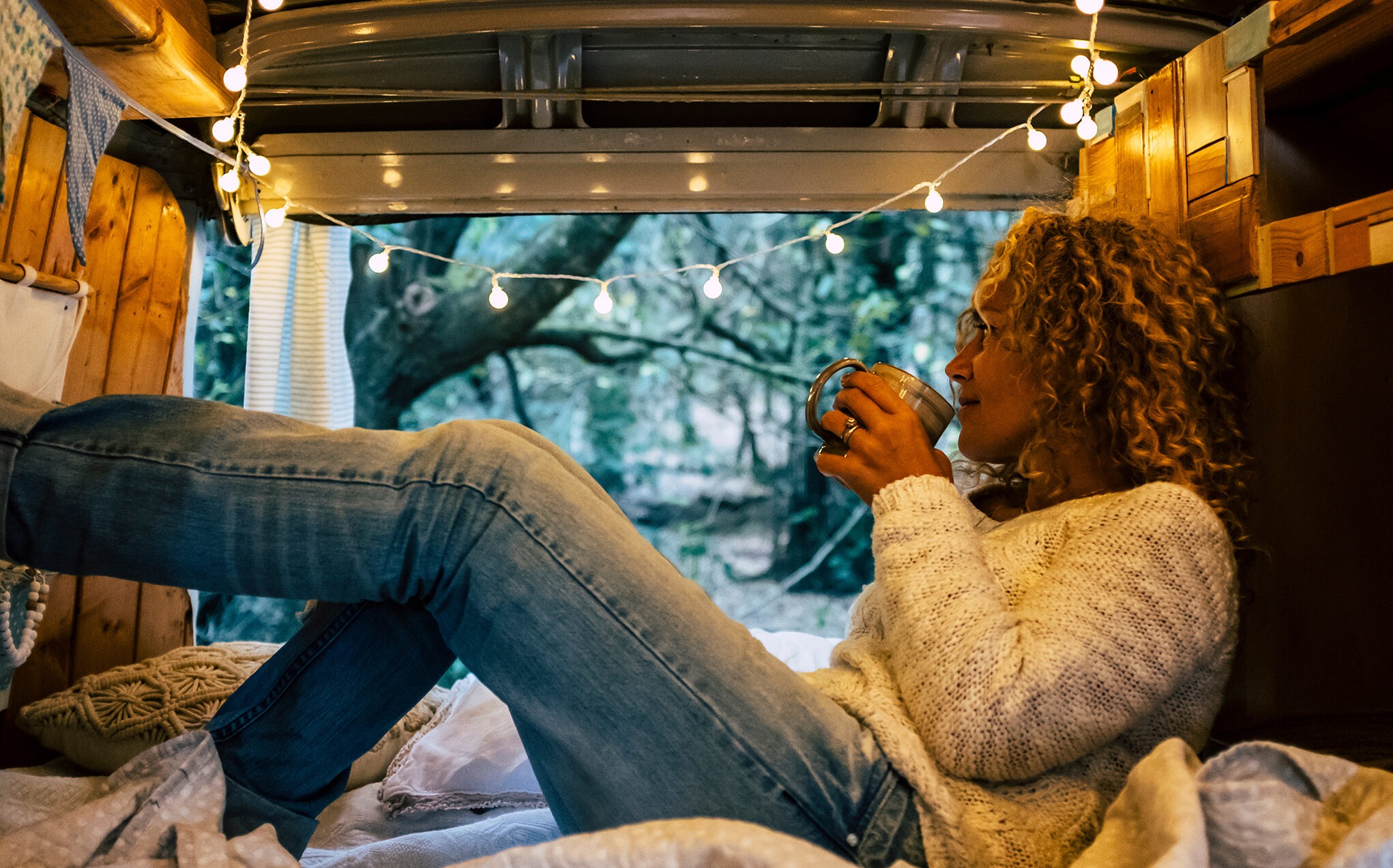 Relaxed adult woman inside a vintage wooden van enjoy the natoure outdoor and the travel lifestyle - tourist and vehicle camping life with forest view outside - wanderlust and van life modern alternative concept