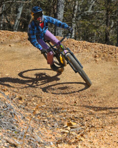 Mountain biker navigating a sharp curve at Howler Bike Park in Walnut Shade, MO, showcasing the physical and mental health benefits of mountain biking, including improved fitness, muscle strength, and stress relief in a natural setting.